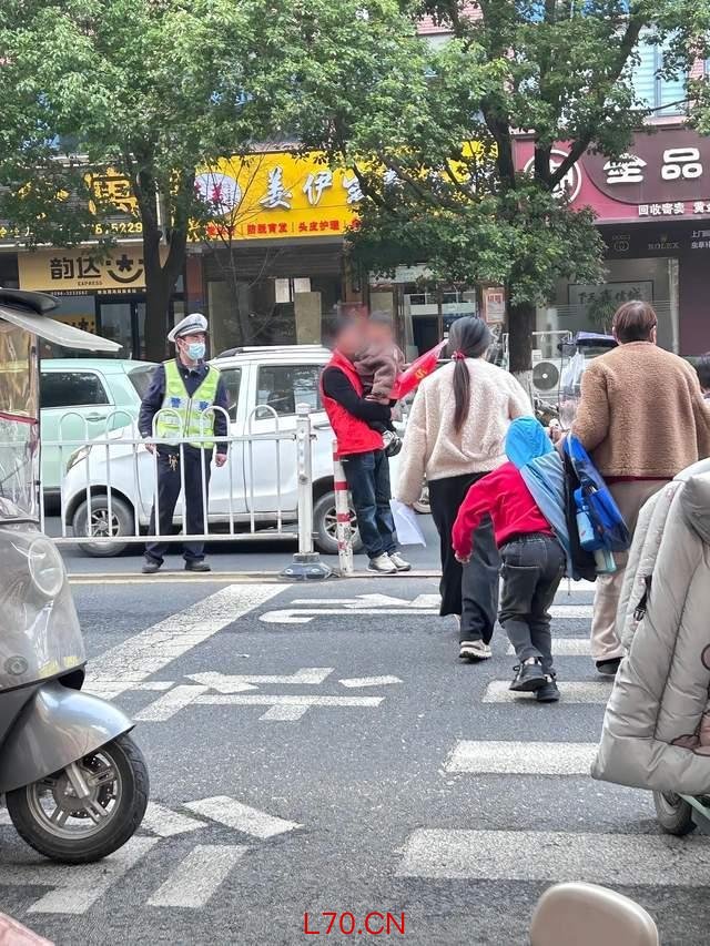 老人抱小孩在马路中间参与护学岗